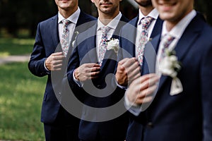 Elegant groom`s men with sttlish flowers tie. white Flowers in buttonhole, the groom`s men are dressed in a dark suit. Wedding d