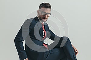 Elegant guy in his forties with glasses crossing legs while sitting