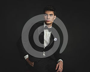 elegant handsome young man wearing black suit looking to side