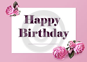 Elegant Happy Birthday Greeting Card. Text on white sheet of paper and isolated flowers of peonies on a pink background.