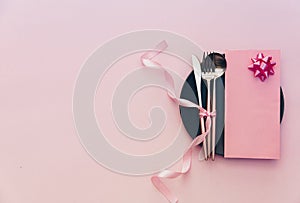 Elegant holiday table place setting with card and cutlery closeup on pink background.