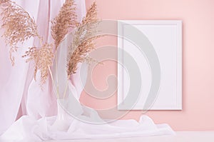 Elegant home decoration - blank photo frame for poster hanging on pink wall, curtain, beige fluffy reeds on white wooden shelf.
