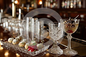 elegant hors doeuvres next to crystal cocktail glasses on a bar