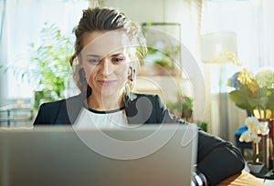 Elegant housewife surfing web on laptop while sitting on couch