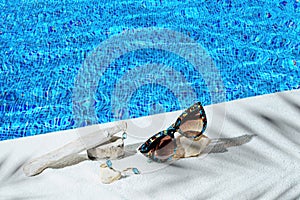 Elegant jewellery set of gold earrings and ring with blue topaz with sunglasses near swimming pool with transparent water as a