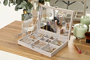 Elegant jewelry box with beautiful bijouterie, cosmetics and candles on wooden table