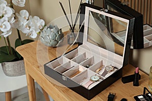 Elegant jewelry box with beautiful bijouterie, cosmetics and stylish accessories on dressing table in room