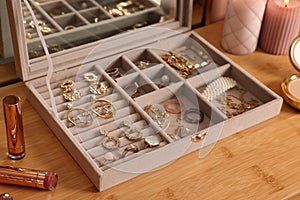 Elegant jewelry box with beautiful bijouterie and makeup products on wooden table