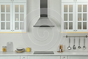 Elegant kitchen interior with modern range hood over cooktop and furniture
