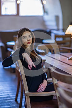 Elegant lady in a black dress, in a restaurant alone. Girl in a cafe in a black dress