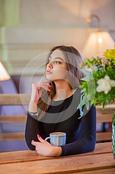 Elegant lady in a black dress, in a restaurant alone. Girl in a cafe in a black dress
