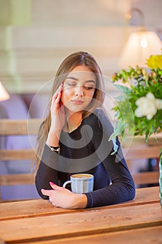 Elegant lady in a black dress, in a restaurant alone. Girl in a cafe in a black dress