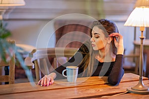 Elegant lady in a black dress, in a restaurant alone. Girl in a cafe in a black dress