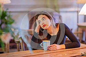 Elegant lady in a black dress, in a restaurant alone. Girl in a cafe in a black dress