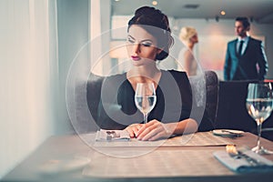 Elegant lady with glass of wine alone in restaurant