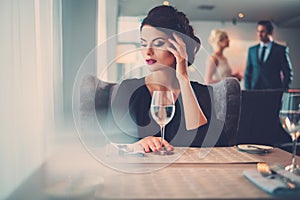 Elegant lady with glass of wine alone in restaurant