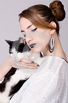 Elegant lady holding black and white cat with yellow eyes