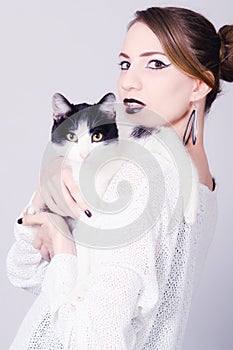 Elegant lady holding black and white cat with yellow eyes