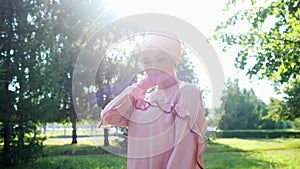 Elegant lady in long purple dress and hijab walks along park