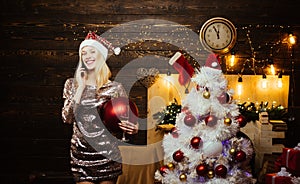 Elegant lady over Christmas tree lights background. Smiling woman decorating Christmas tree at home. Woman new year eve.