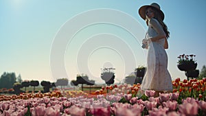 Elegant lady spending time in nature. Romantic woman smiling in flowers garden.