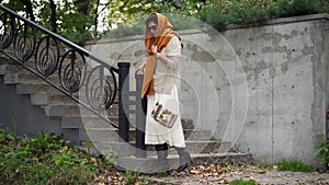 Elegant lady in stylish clothes and sunglasses walking downstairs in park looking away. Wide shot portrait of confident