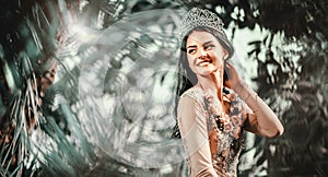 Elegant lady with tiara on a head posing in a forest