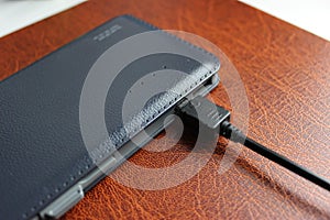 Elegant Leather Trimmed Power Bank Charging On Brown Leather Paper Folder Detailed Stock Photo