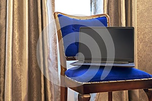 Elegant lightweight laptop with blank screen on vintage blue tapestry chair