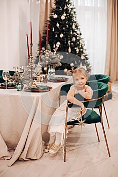 Elegant little girl in festive dress at Christmas table.