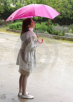 Elegant little girl is in the rain with an umbrella