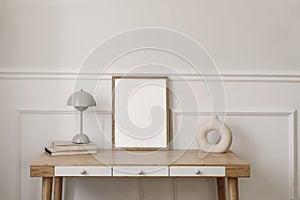 Elegant living room, home office. Modern round vase, beige lamp and old books. Blank wooden picture frame mockup. Bamboo