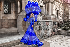 Elegant luxury fashion. Glamour, stylish elegant woman in long gown sequin dress is holding bunch of balloons. Female model in