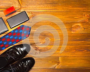 The elegant male set: men`s shoes, leather belt, on the wooden background.