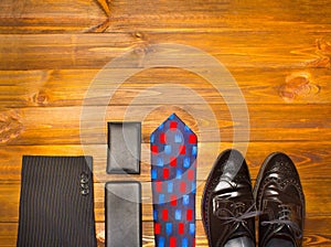 The elegant male set: men`s shoes, leather belt, on the wooden background.