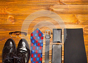 The elegant male set: men`s shoes, leather belt, on the wooden background.