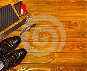 The elegant male set: men`s shoes, leather belt, on the wooden background.