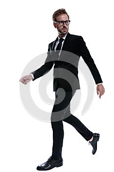 Elegant man in black suit looking to side and walking