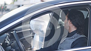 Elegant man on driver's seat in car watching woman walking out leaving. Side view portrait of Caucasian male drivers