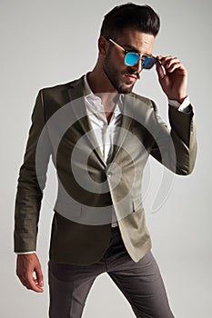 Elegant man fixes his sunglasses and looks to side