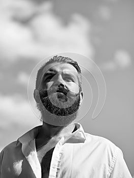 Elegant man`s hairdress. Bearded man on blue sky