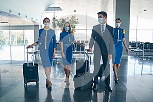 Elegant man and stewardesses with their luggage