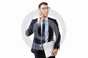 Elegant man, in a suit and glasses, talking on the phone and holding a laptop in his hand, on a white background