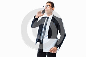 Elegant man, in a suit and glasses, talking on the phone and holding a laptop in his hand, on a white background