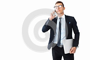 Elegant man, in a suit and glasses, talking on the phone and holding a laptop in his hand, on a white background