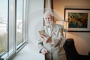 Elegant man in a suit looking at the smartphone with anticipation