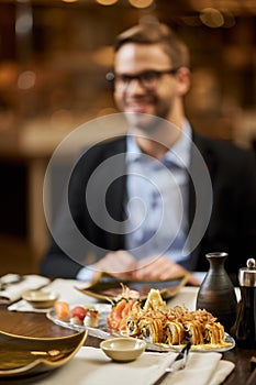Elegant man about to dine on tasty sushi at a restaurant