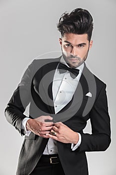 Elegant man in tuxedo closing his jacket