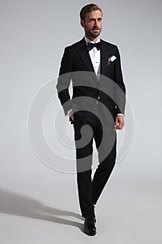 Elegant man in tuxedo standing with hand in pocket