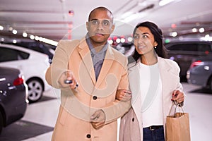 Elegant married couple in an underground parking lot opens car using alarm key fob